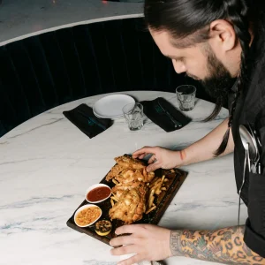 Chef carefully placing a fried seafood platter on a dining table inside Ciel Restaurant and Lounge.